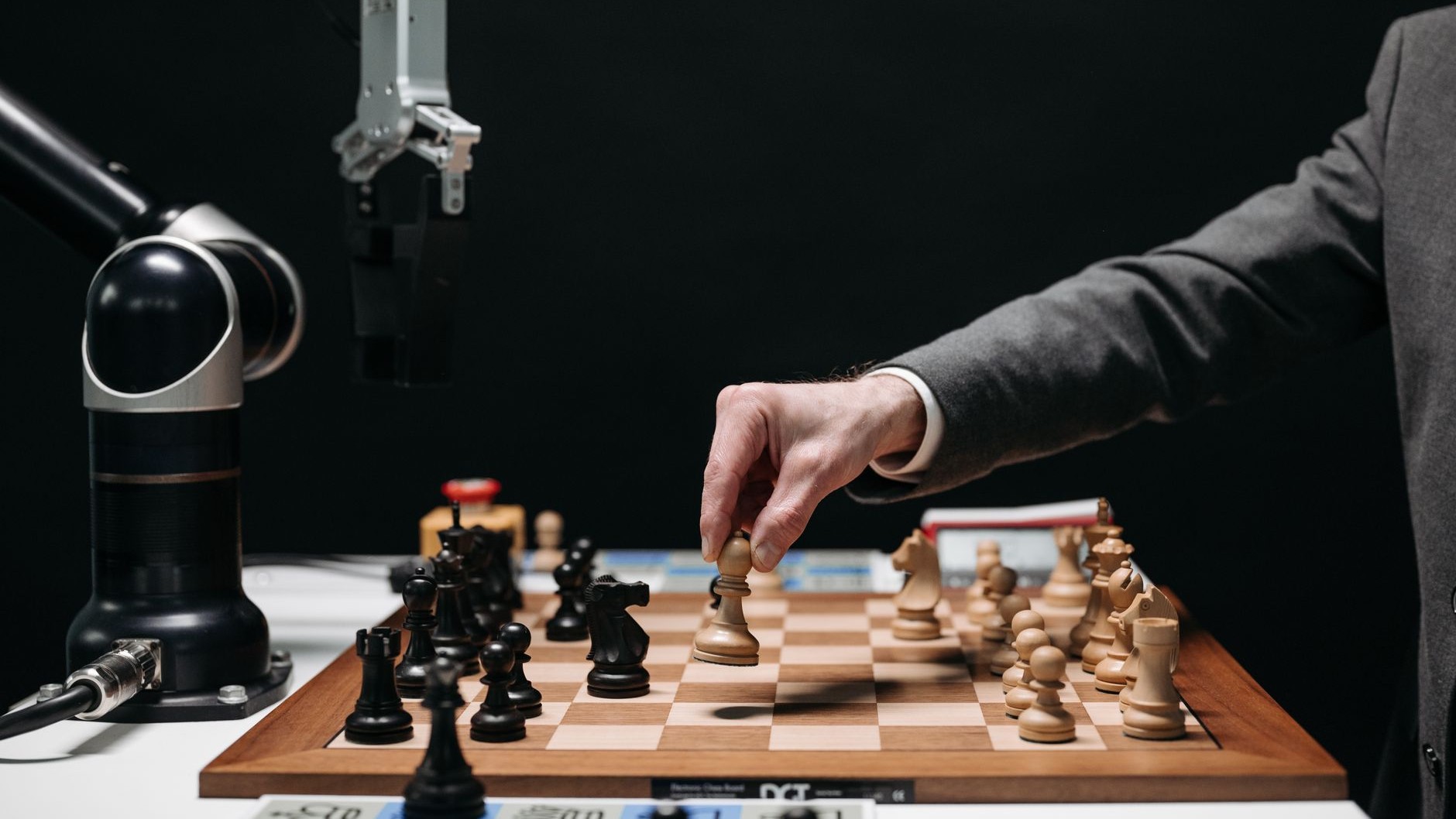 A robotic arm faces a human player across a chessboard
