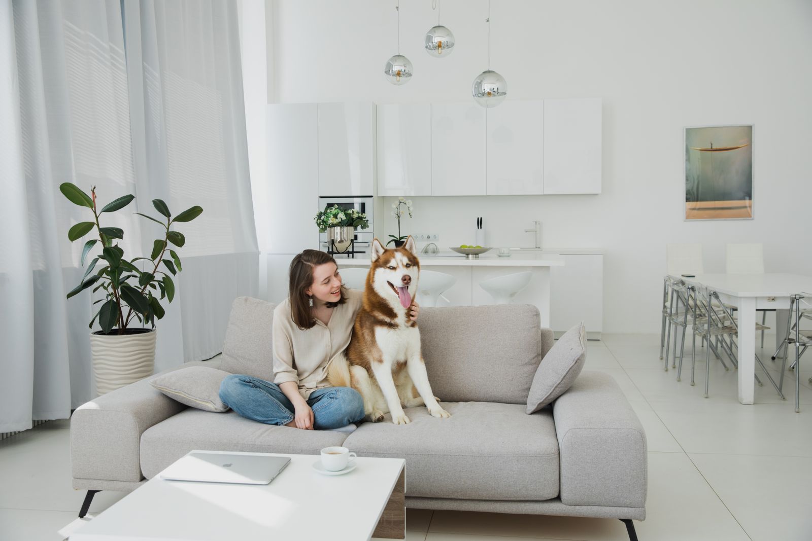 A smiling woman hugging a husky on a sofa